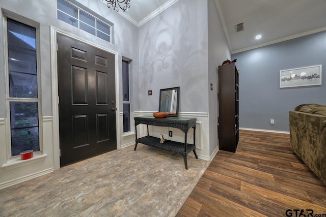 entrance foyer with baseboards, visible vents, dark wood-type flooring, crown molding, and a chandelier