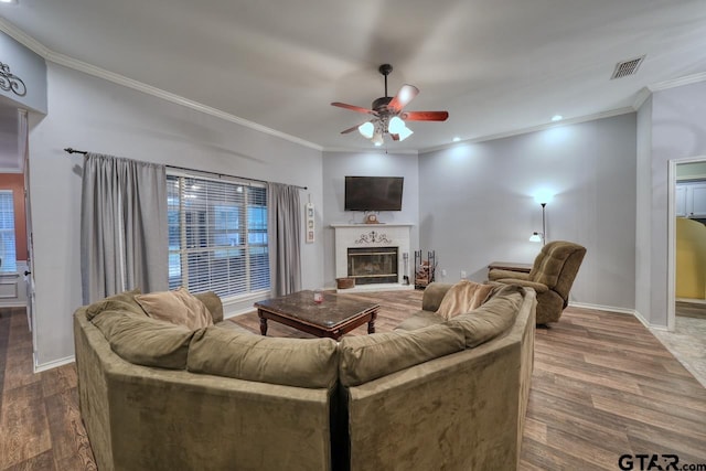 living area with baseboards, visible vents, a glass covered fireplace, ceiling fan, and wood finished floors