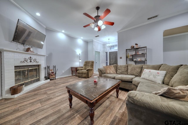 living room with visible vents, ornamental molding, a brick fireplace, wood finished floors, and baseboards