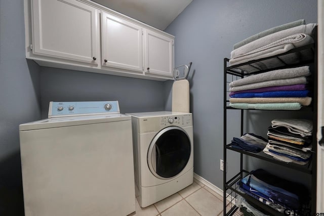 laundry area featuring cabinet space, light tile patterned floors, baseboards, and separate washer and dryer