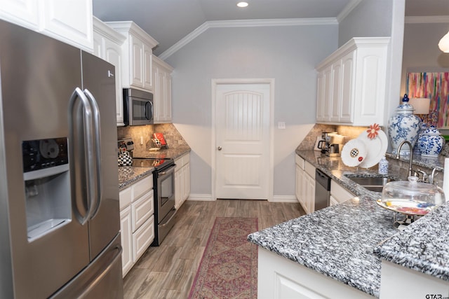 kitchen with stainless steel appliances, lofted ceiling, sink, white cabinetry, and dark stone countertops