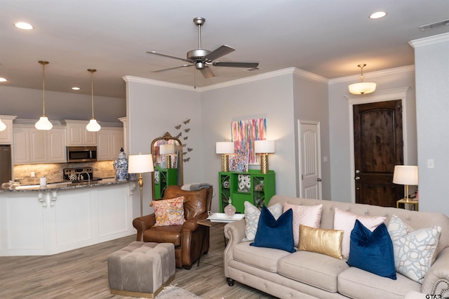 living room featuring ornamental molding, light hardwood / wood-style floors, ceiling fan, and sink