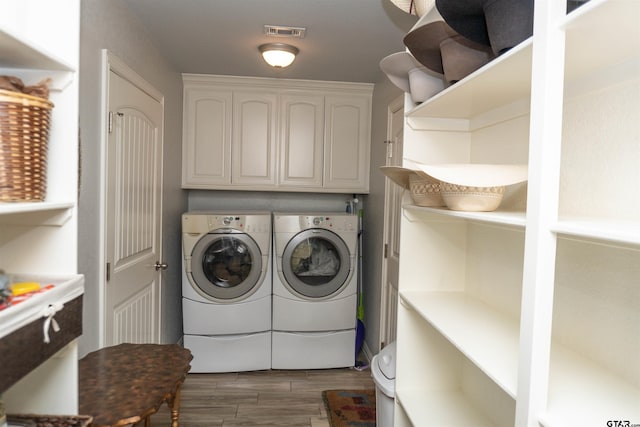 laundry room featuring dark wood-type flooring, cabinets, and washer and dryer