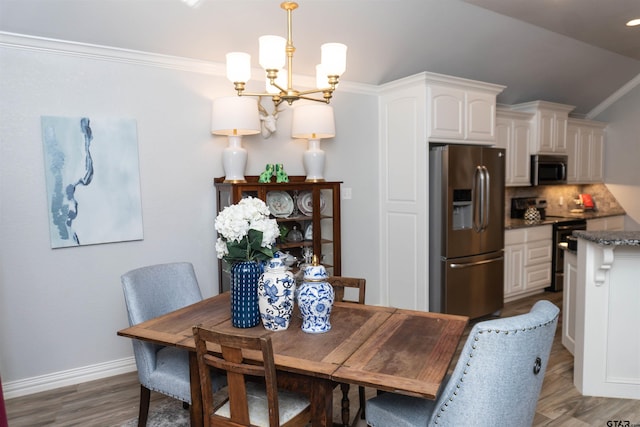 dining space with hardwood / wood-style flooring, a chandelier, lofted ceiling, and ornamental molding