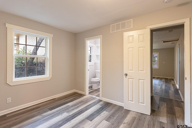 unfurnished bedroom featuring hardwood / wood-style floors, connected bathroom, and a closet