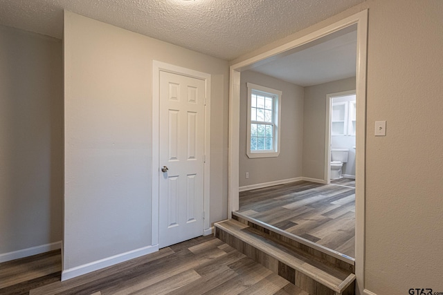 hallway with dark wood-type flooring and a textured ceiling