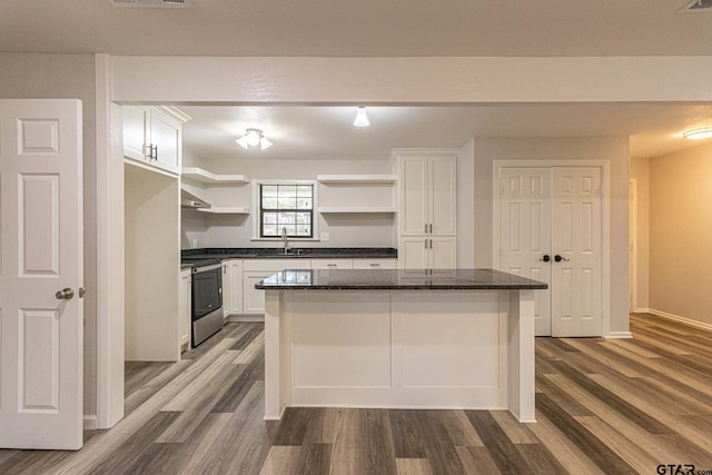 kitchen featuring sink, dark hardwood / wood-style floors, a kitchen island, white cabinets, and stainless steel stove