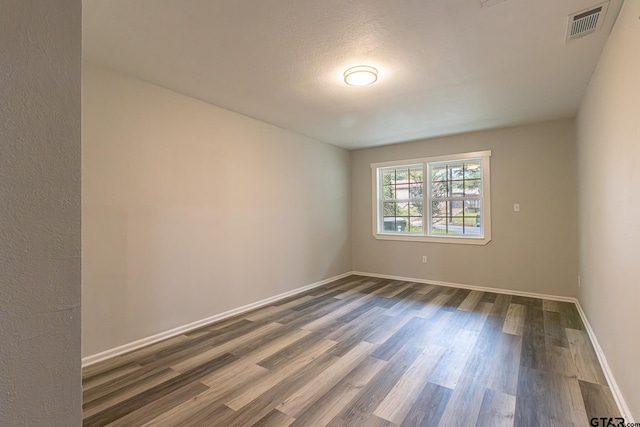 empty room with dark hardwood / wood-style flooring and a textured ceiling