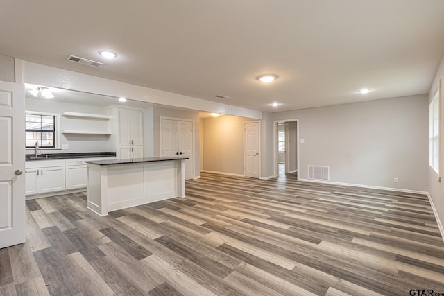 kitchen with white cabinetry, hardwood / wood-style floors, sink, and a kitchen island