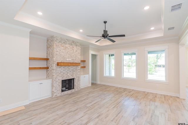 unfurnished living room featuring a tray ceiling, light wood-type flooring, visible vents, and crown molding
