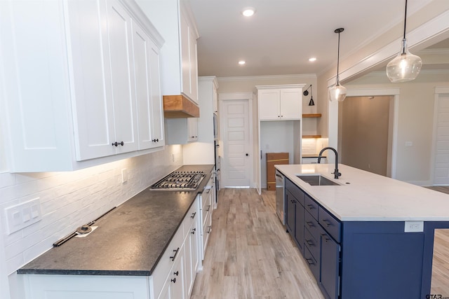 kitchen featuring crown molding, tasteful backsplash, a sink, blue cabinets, and stainless steel appliances