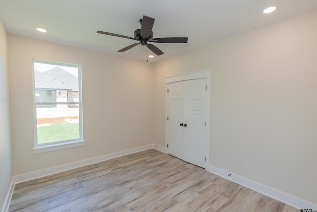 unfurnished room featuring light wood finished floors, a ceiling fan, baseboards, and a healthy amount of sunlight