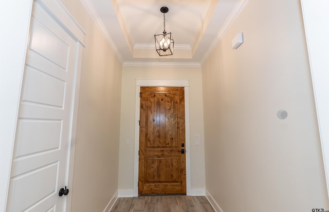 doorway with baseboards, ornamental molding, a chandelier, and light wood-style floors
