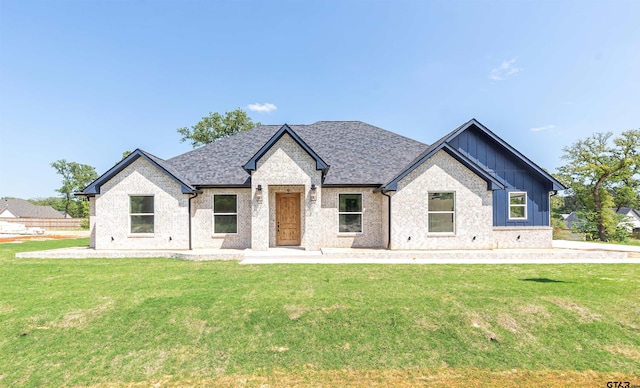 view of front of house with board and batten siding, brick siding, and a front yard