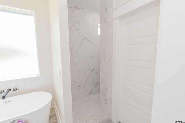 full bathroom with a freestanding bath, plenty of natural light, and a marble finish shower