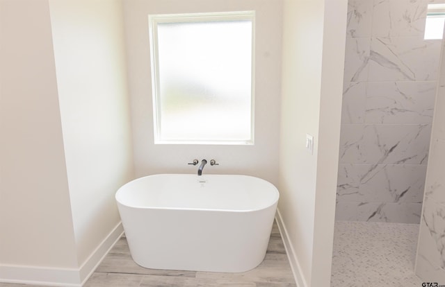 full bathroom featuring a soaking tub, baseboards, and a walk in shower