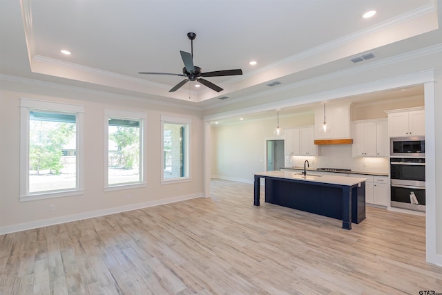 kitchen with stainless steel appliances, a tray ceiling, visible vents, a sink, and a breakfast bar area