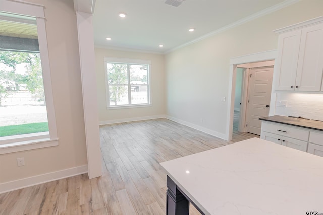 kitchen with ornamental molding, a wealth of natural light, and light stone counters