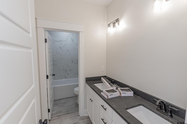 full bathroom featuring double vanity, toilet, wood finished floors, and a sink