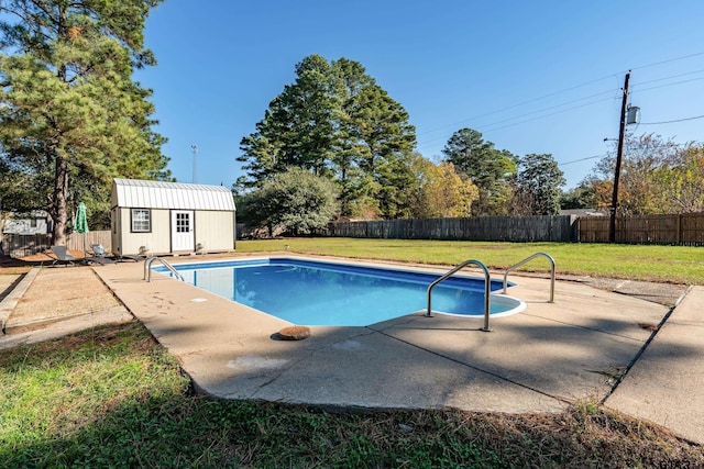 view of pool with a lawn, a patio area, and a storage shed