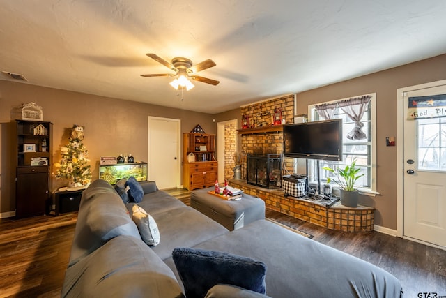 living room featuring dark hardwood / wood-style flooring, a brick fireplace, and ceiling fan