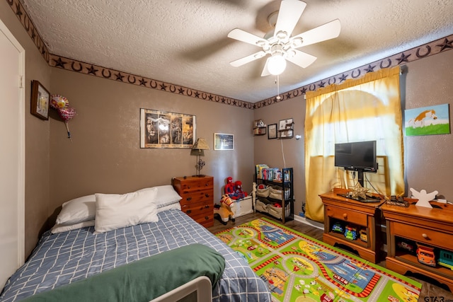 bedroom with ceiling fan, wood-type flooring, and a textured ceiling