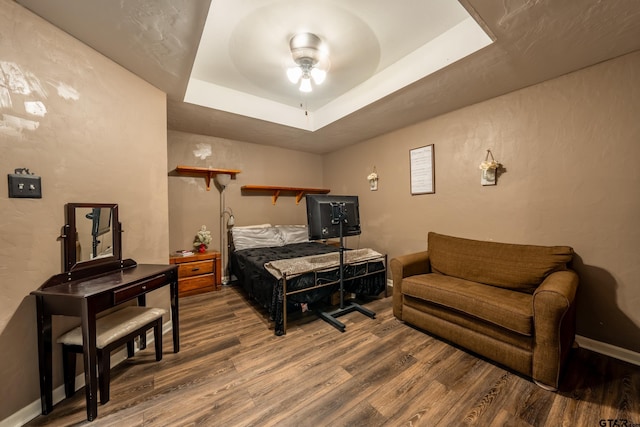 bedroom featuring hardwood / wood-style flooring, ceiling fan, and a tray ceiling