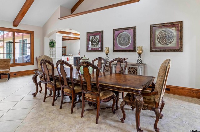 tiled dining area with beamed ceiling and high vaulted ceiling