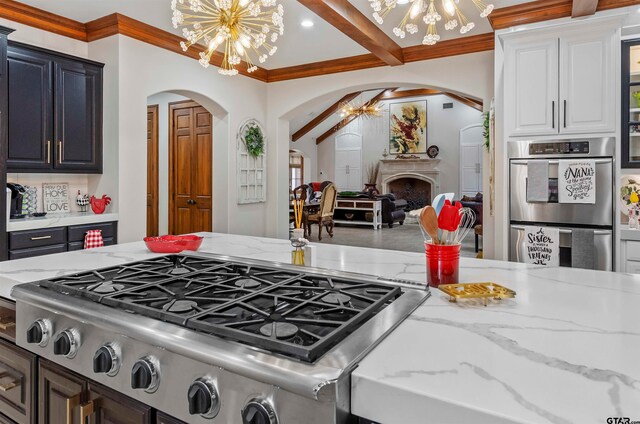 kitchen with white cabinets, crown molding, appliances with stainless steel finishes, a notable chandelier, and beam ceiling