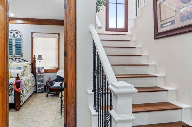 staircase with tile patterned flooring and crown molding