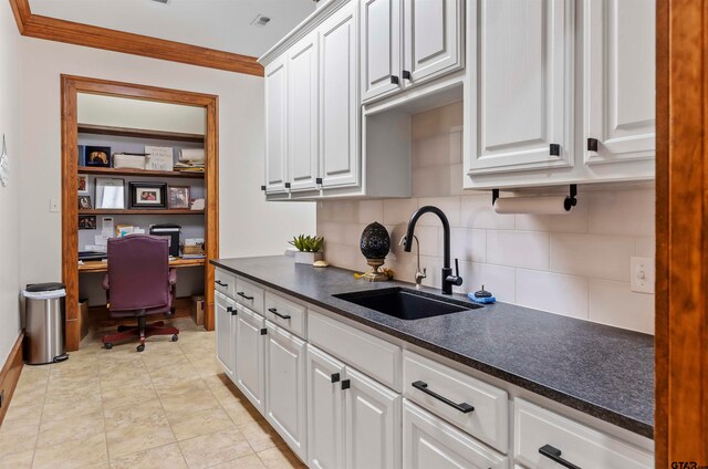 kitchen featuring tasteful backsplash, ornamental molding, sink, light tile patterned floors, and white cabinets