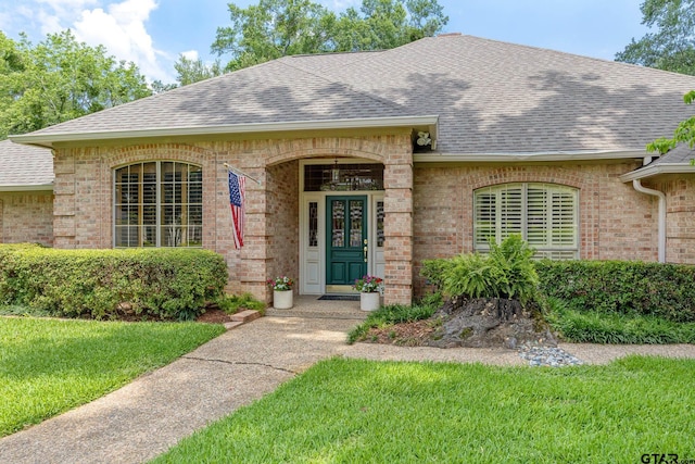 1807 Royal Oak Dr, Tyler, TX 75703 - doorway to property with roof with shingles, brick siding, and a lawn
