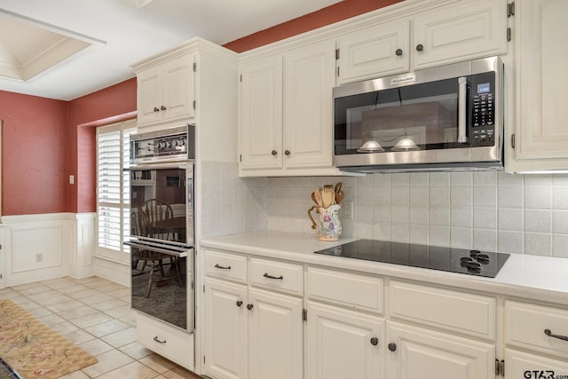 1807 Royal Oak Dr, Tyler, TX 75703 - kitchen with stainless steel microwave, double wall oven, black electric cooktop, light countertops, and wainscoting
