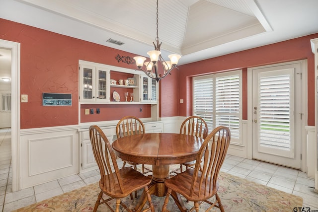 1807 Royal Oak Dr, Tyler, TX 75703 - dining space with wainscoting, light tile patterned floors, a chandelier, a raised ceiling, and a decorative wall