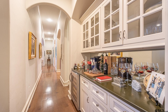 bar featuring dark hardwood / wood-style flooring, wine cooler, and white cabinets