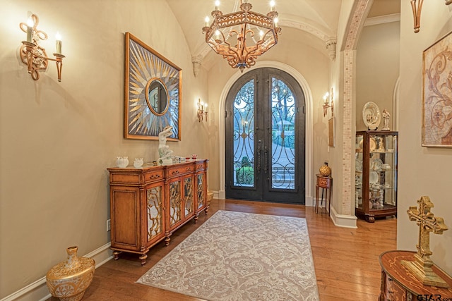 foyer with a chandelier, lofted ceiling, french doors, and hardwood / wood-style flooring