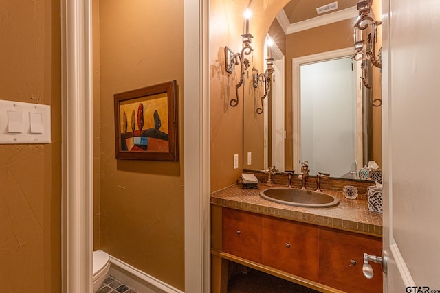 bathroom with toilet, vanity, and crown molding