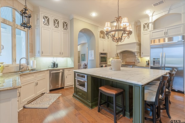 kitchen with pendant lighting, appliances with stainless steel finishes, white cabinetry, and a center island