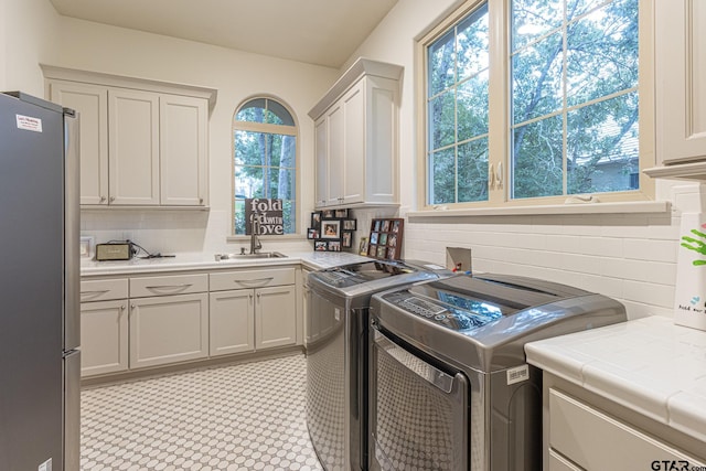 washroom with washing machine and dryer, cabinets, and sink