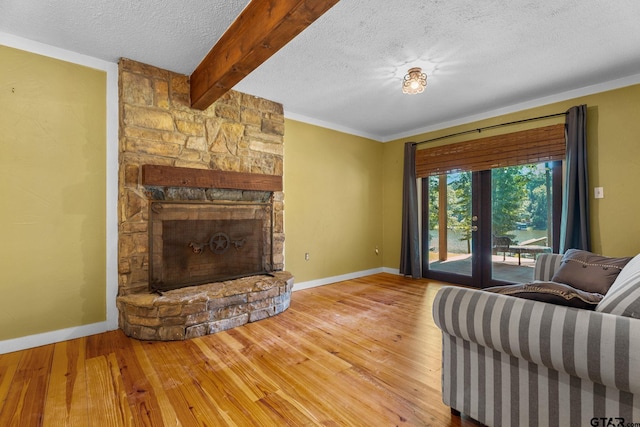 living room with wood-type flooring, beam ceiling, a stone fireplace, and a textured ceiling
