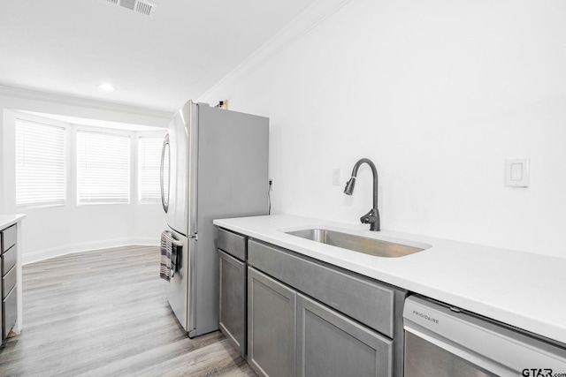 kitchen with crown molding, sink, dishwashing machine, and stainless steel refrigerator