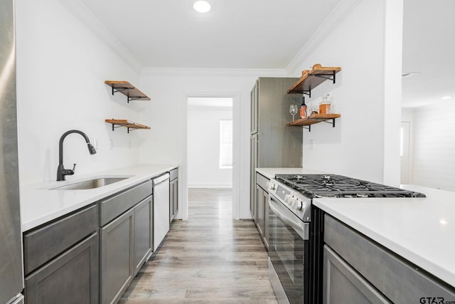 kitchen featuring stainless steel appliances, crown molding, sink, and light hardwood / wood-style flooring