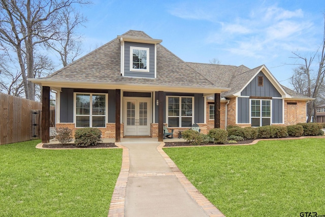 view of front of house featuring a front yard, french doors, brick siding, and fence