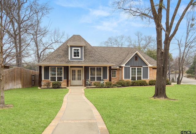 view of front of house with french doors, roof with shingles, a front lawn, and brick siding