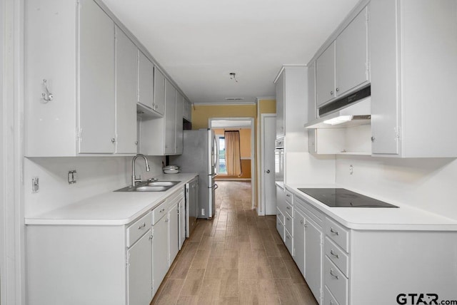 3316 Lynnwood Dr, Tyler, TX 75701 - kitchen with black electric cooktop, a sink, under cabinet range hood, light countertops, and light wood-type flooring