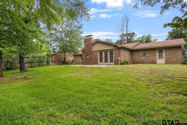 3316 Lynnwood Dr, Tyler, TX 75701 - back of property with french doors, a chimney, brick siding, and a patio area