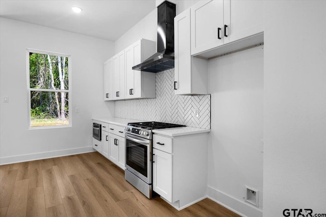 17314 Fm 2767, Tyler, TX 75705 - kitchen with wall chimney range hood, stainless steel gas range, light wood finished floors, decorative backsplash, and light countertops