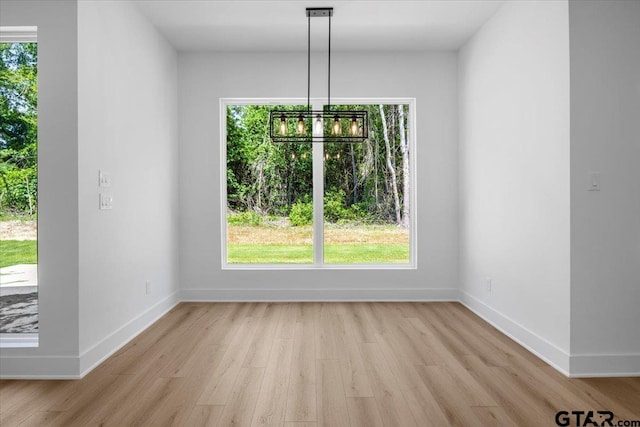 17314 Fm 2767, Tyler, TX 75705 - unfurnished dining area with light wood-type flooring, a chandelier, baseboards, and healthy amount of natural light