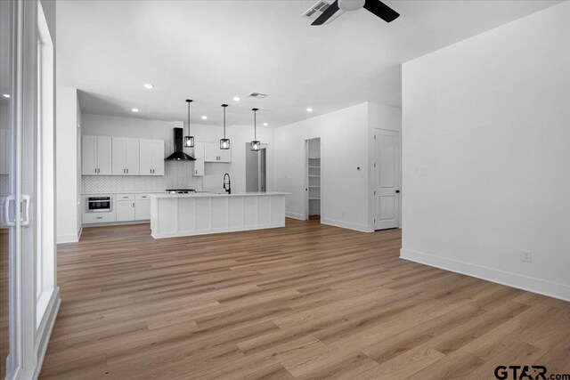 17314 Fm 2767, Tyler, TX 75705 - unfurnished living room with a ceiling fan, recessed lighting, light wood-type flooring, baseboards, and a sink