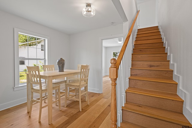 dining space featuring baseboards, light wood finished floors, and stairway